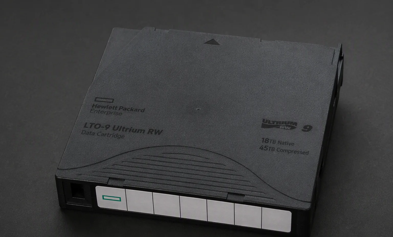 LTO-9 Ultrium data cartridge black case with label area, macro studio shot on dark surface.