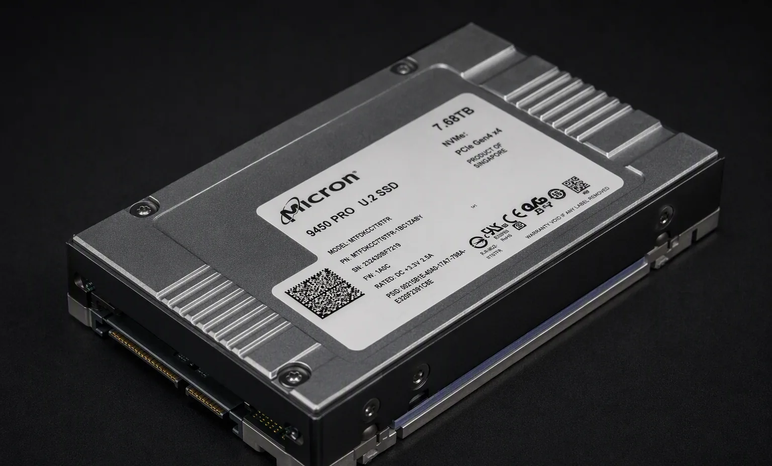 enterprise U.2 NVMe SSD with metal heatsink cover showing screws and thermal pad edge, dark studio.