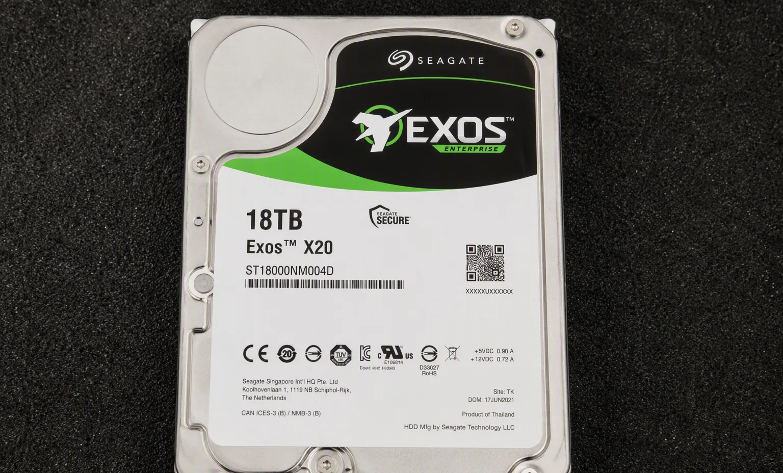 Seagate Exos X20 enterprise hard drive 18TB label side, resting on dark anti-static foam, macro detail, studio lighting.