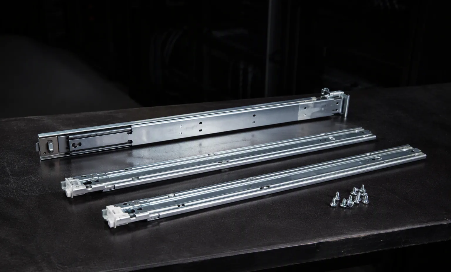 2U server rail kit with inner rails and screws laid out on dark bench, dark studio.