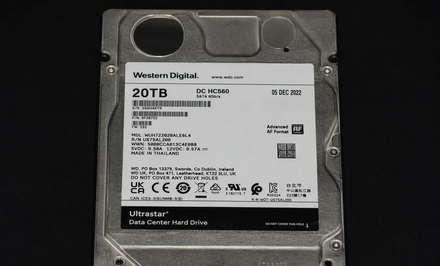 Western Digital Ultrastar DC HC560 20TB enterprise HDD top label view, dark studio macro shot.